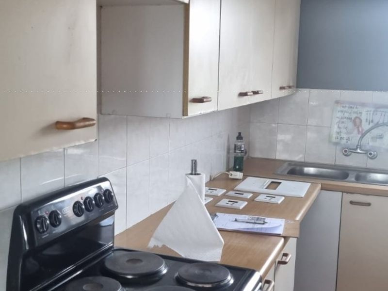 A functional kitchen featuring laminate countertops, built-in cabinetry, a double bowl sink, and a freestanding electric stove with a tiled backsplash.