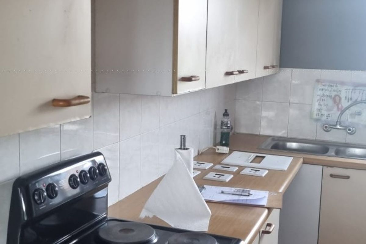 A functional kitchen featuring laminate countertops, built-in cabinetry, a double bowl sink, and a freestanding electric stove with a tiled backsplash.