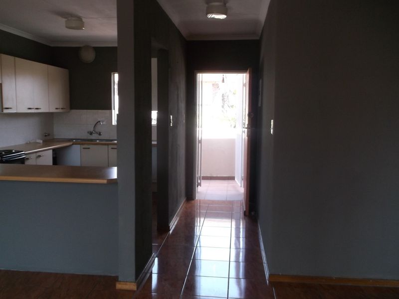 An open plan kitchen area featuring dark painted walls, tiled flooring, and built-in cabinetry, leading directly to an exterior balcony.