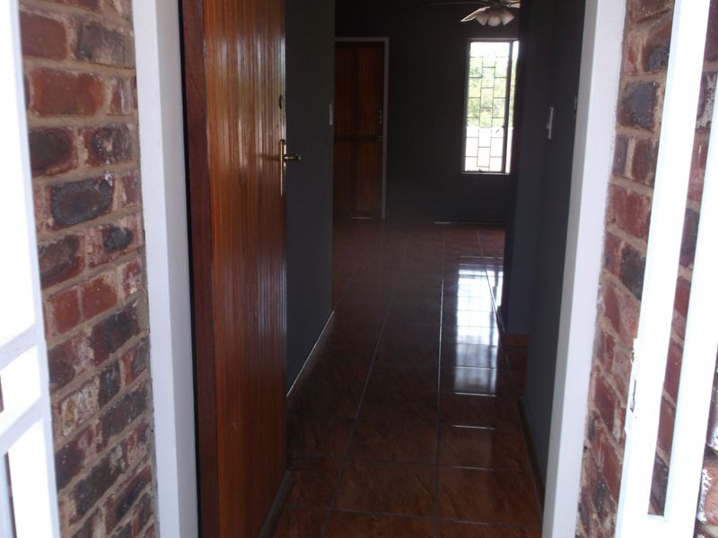 Entrance hallway featuring tiled flooring, exposed brick accents, and a wooden door leading into the interior living space.