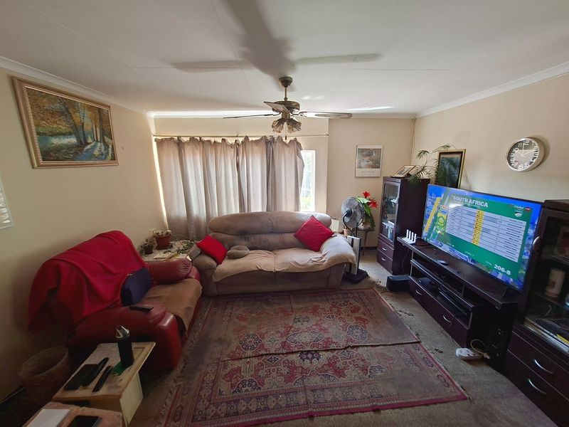 A living room featuring a ceiling fan and neutral wall finishes, providing a functional space for relaxation.