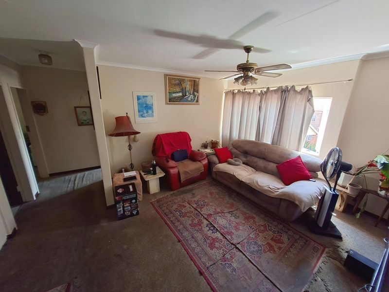 A living room area featuring a ceiling fan and carpeted flooring, requiring updates to finishes to enhance the space.