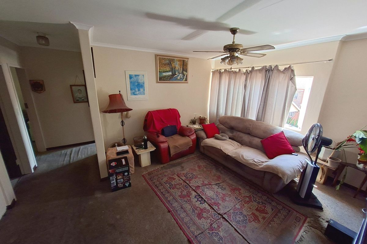 A living room area featuring a ceiling fan and carpeted flooring, requiring updates to finishes to enhance the space.
