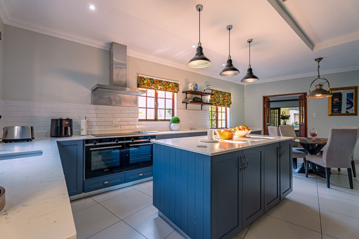 Modern kitchen featuring a large central island, high-end built-in ovens, sleek quartz countertops, and stylish pendant lighting, creating a functional and elegant culinary space.