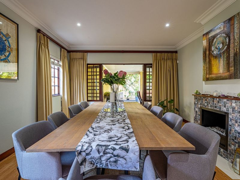 Elegant dining room featuring hardwood flooring, crown molding, recessed lighting, and a distinctive fireplace with a decorative tile surround, opening to an outdoor area.