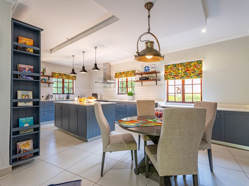 Spacious open-plan kitchen and dining area featuring a central island, modern cabinetry, subway tile backsplash, and stylish pendant lighting.