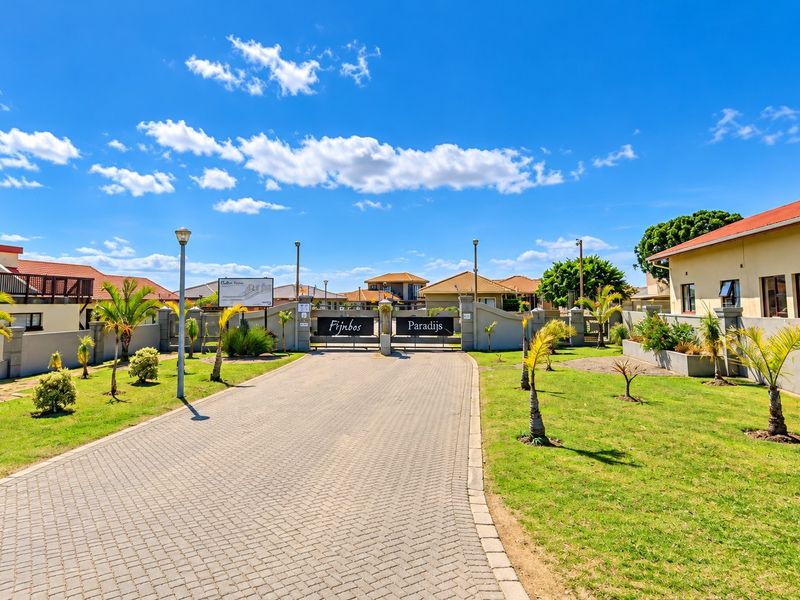 The entrance to Fijnbos Paradijs residential estate, featuring a paved driveway, secure gated access, and well-maintained landscaped grounds.