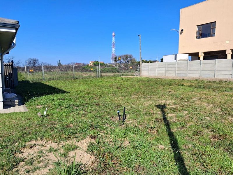 A view of the rear yard area featuring a precast concrete boundary wall, wire mesh fencing, and visible utility connection points on the land.