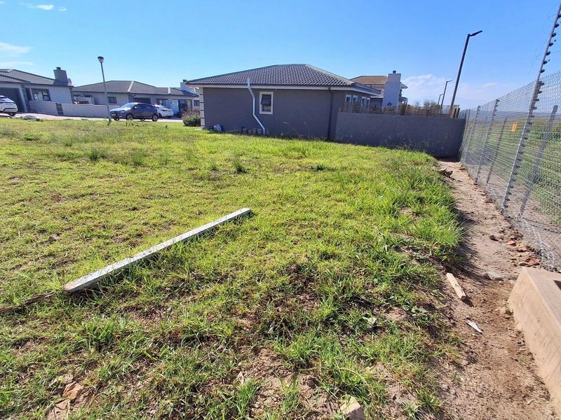 A view of the rear section of the vacant residential plot, featuring perimeter electric fencing and established grass coverage.