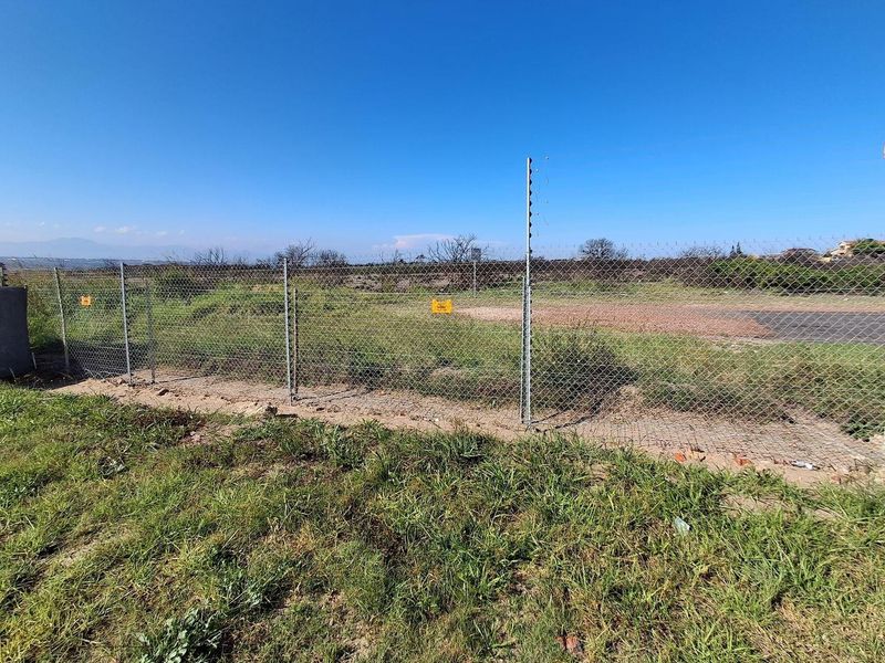 A vacant residential plot secured with chain-link and electric fencing, offering an open landscape ready for development.
