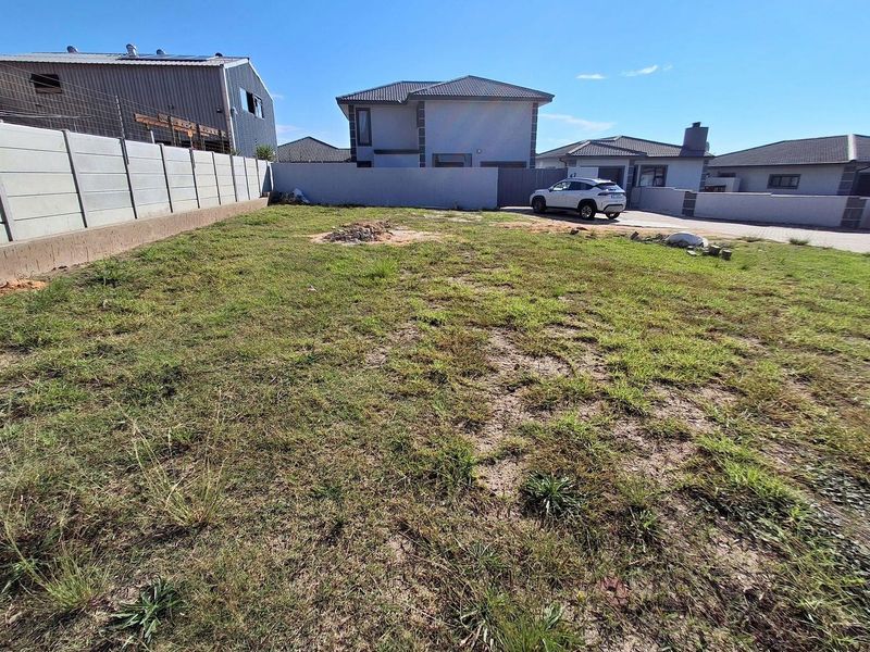 A vacant residential plot featuring a grassed area enclosed by precast concrete boundary walls in a developed suburban neighborhood.