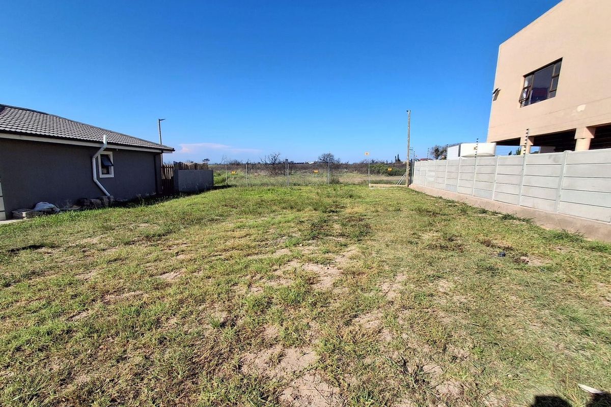 A view of the rear yard area featuring a grass lawn, enclosed by a precast concrete boundary wall and wire mesh fencing.