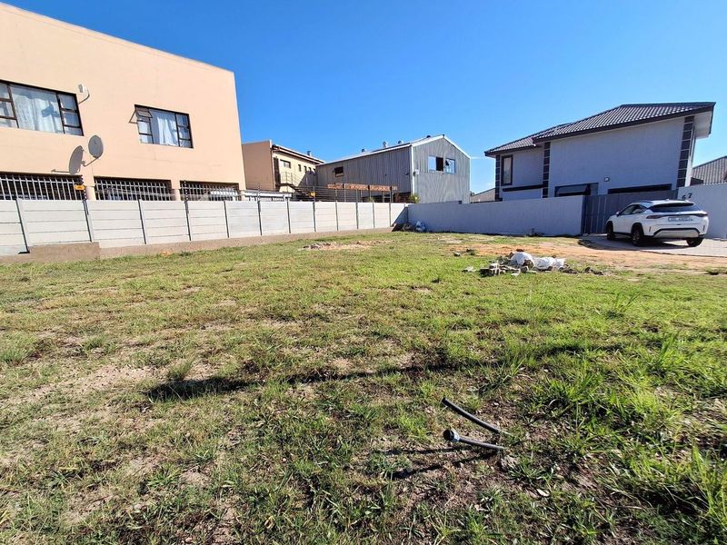 A vacant residential plot featuring a grassed surface, enclosed by precast concrete boundary walls in a developed suburban neighborhood.
