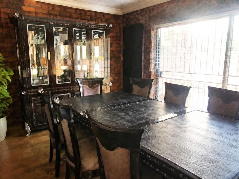 Dining room featuring an exposed brick wall and a large sliding glass door with security bars, providing natural light.
