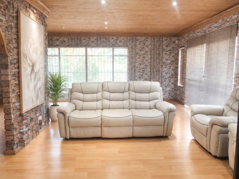 Spacious living room featuring exposed brick wall finishes, warm timber ceiling, and laminate flooring, creating a rustic and inviting atmosphere.