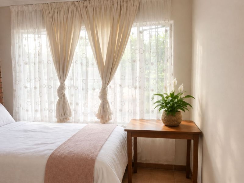 A cozy bedroom featuring an exposed brick accent wall, tiled flooring, and a large window that allows for natural light.