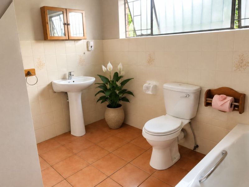 A functional bathroom featuring a pedestal basin, standard toilet, and bathtub with tiled walls and flooring, offering a clean and practical layout.