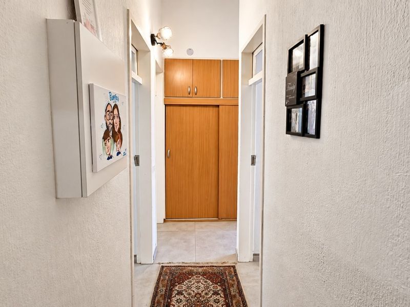 A functional hallway featuring built-in wooden storage cabinetry and tiled flooring, providing efficient access between rooms.