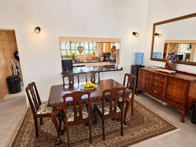 Dining room featuring tiled flooring, wall-mounted lighting, and a convenient pass-through window connecting to the kitchen area.