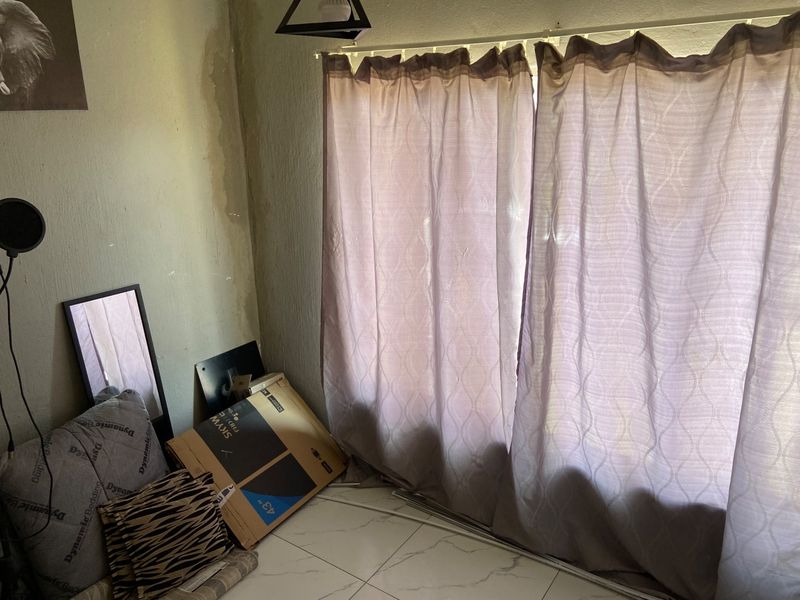 A living area featuring tiled flooring and a sliding door, showing visible water damage on the wall surface.