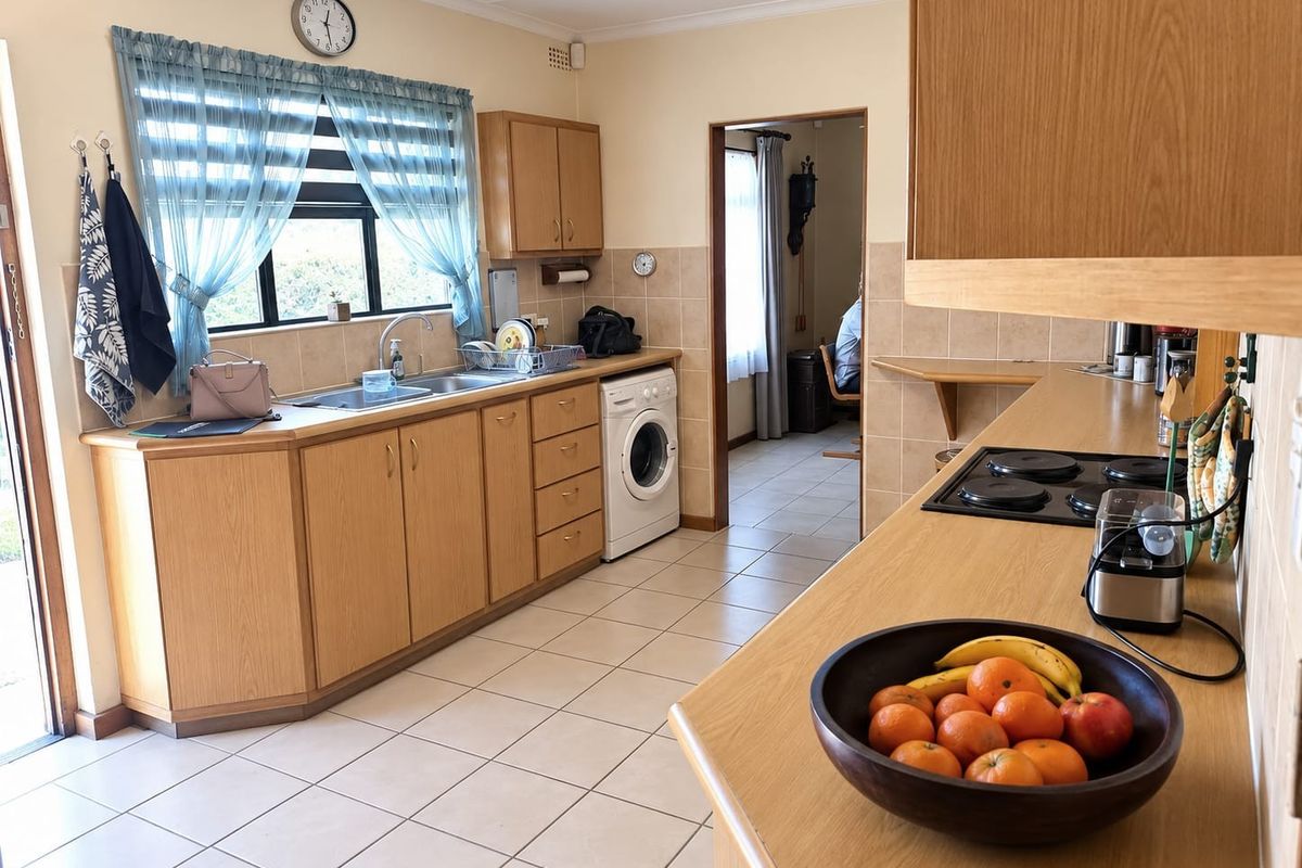 Functional kitchen featuring wooden cabinetry, laminate countertops, tiled backsplash, and integrated laundry plumbing, offering a practical layout with direct access to adjacent living areas.