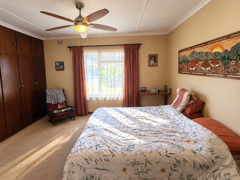 A well-maintained bedroom featuring built-in wooden cabinetry, a ceiling fan, and carpeted flooring, offering a comfortable and functional living space.