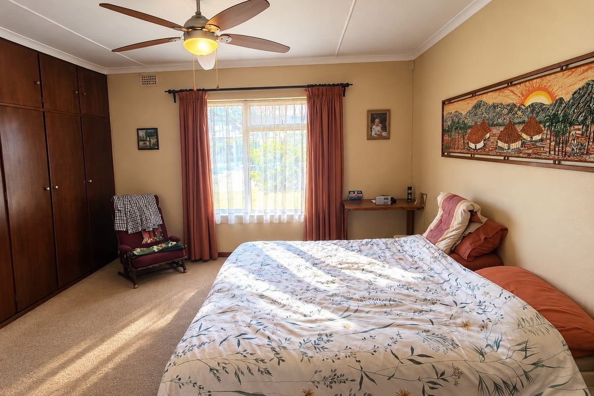 A well-maintained bedroom featuring built-in wooden cabinetry, a ceiling fan, and carpeted flooring, offering a comfortable and functional living space.