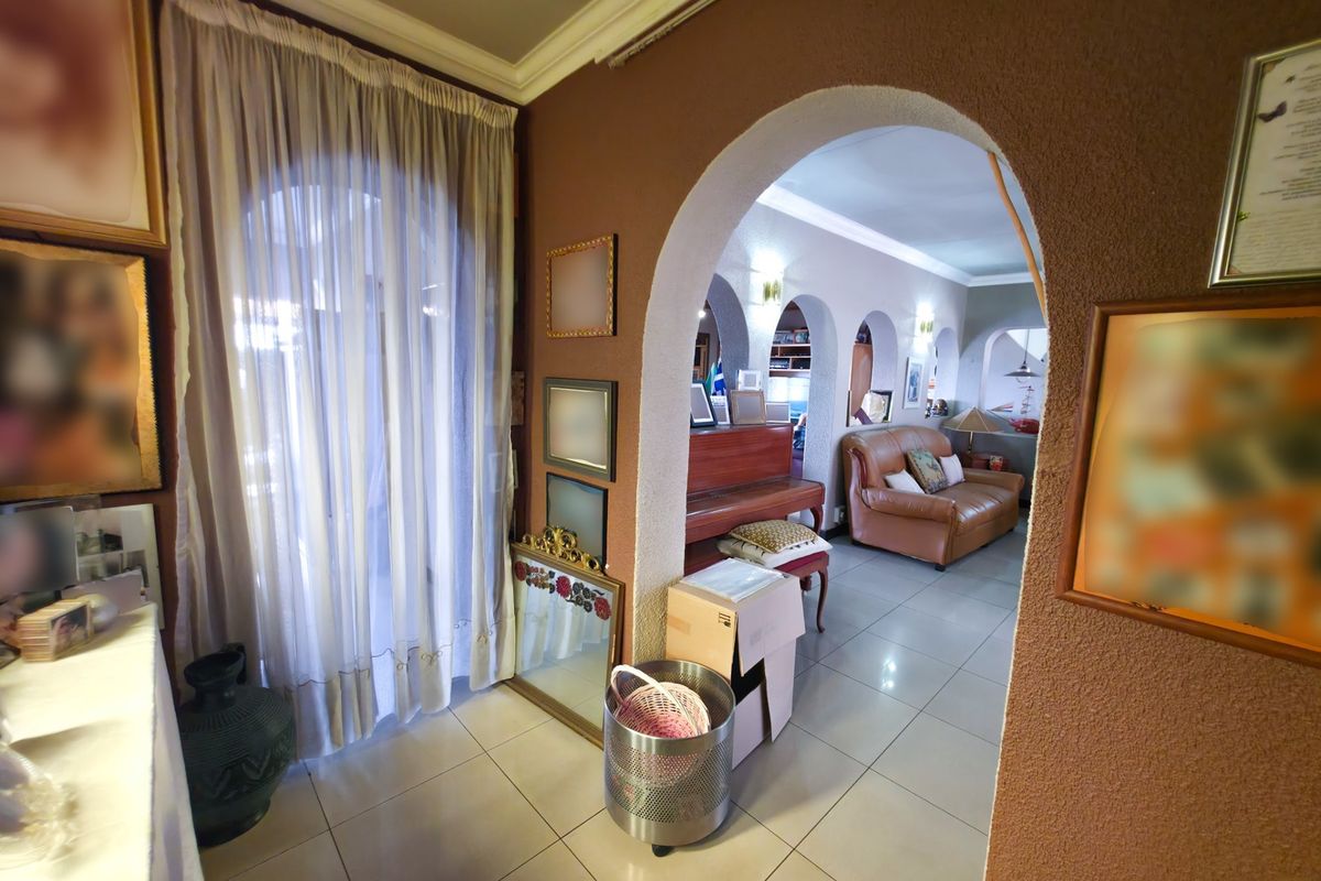 A living area featuring distinctive arched doorways, tiled flooring, and coved ceiling cornices, creating a traditional layout with connected living spaces.