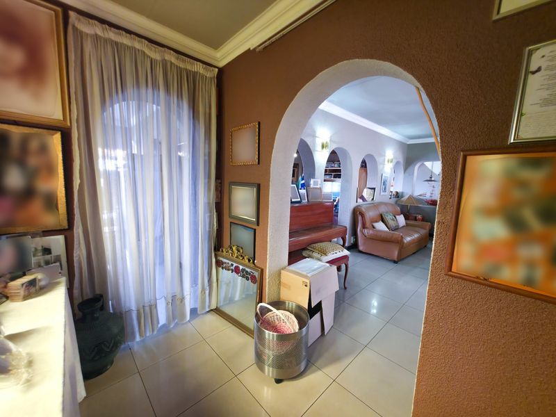 A living area featuring distinctive arched doorways, tiled flooring, and coved ceiling cornices, creating a traditional layout with connected living spaces.