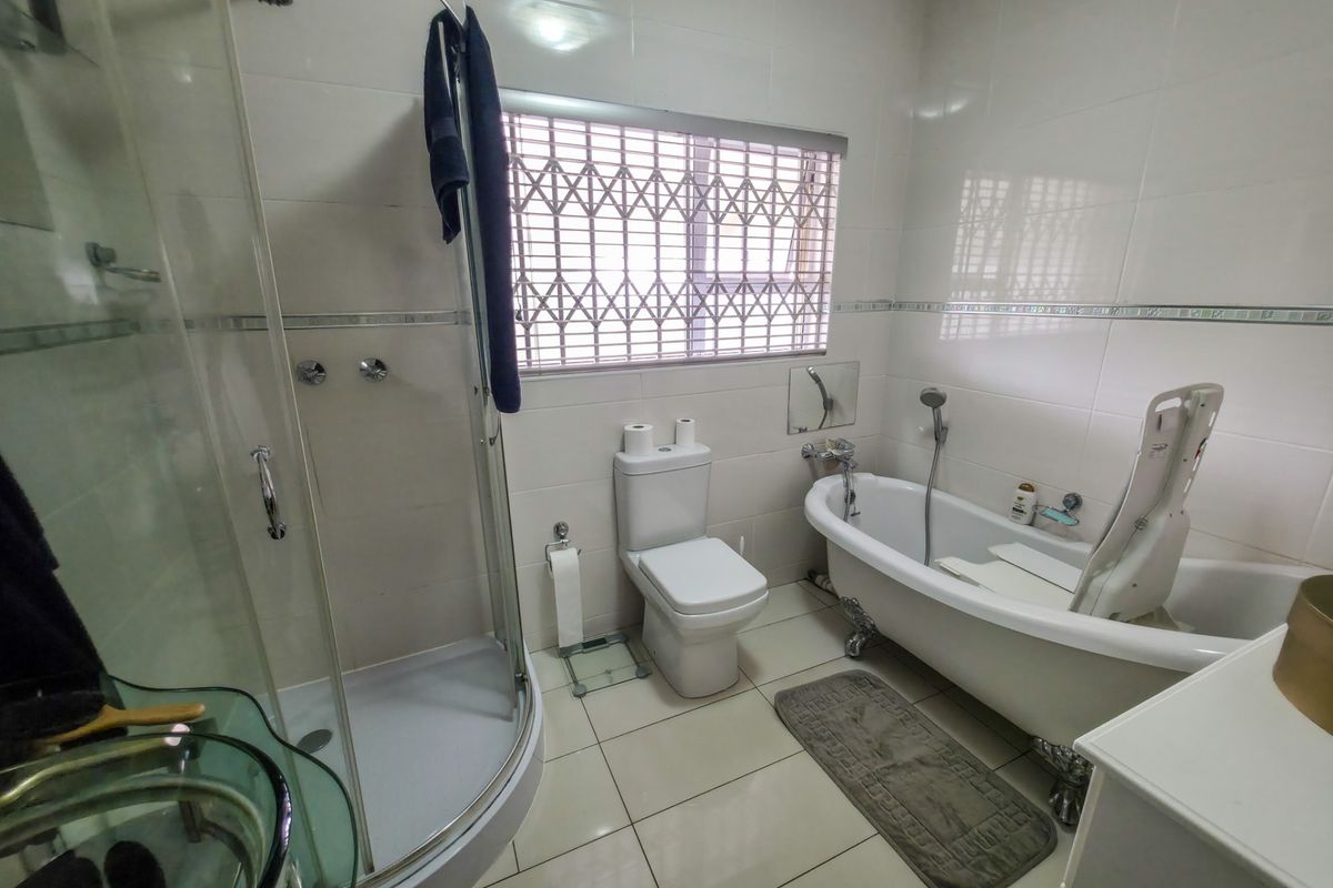 A well-appointed bathroom featuring a separate shower enclosure, a classic clawfoot bathtub, and a toilet, finished with neutral wall and floor tiles.
