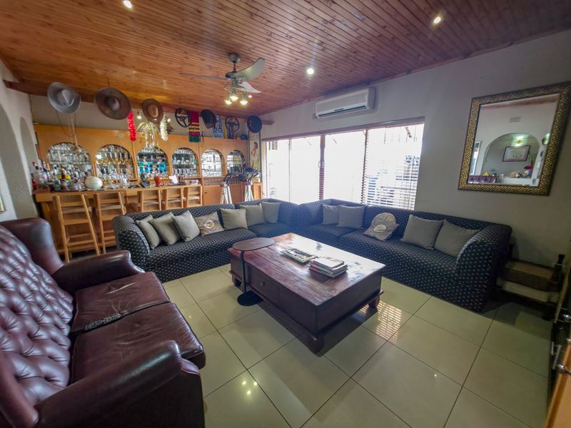 Spacious entertainment room featuring a built-in bar, timber-clad ceiling, tiled flooring, and integrated air conditioning, perfect for hosting guests.