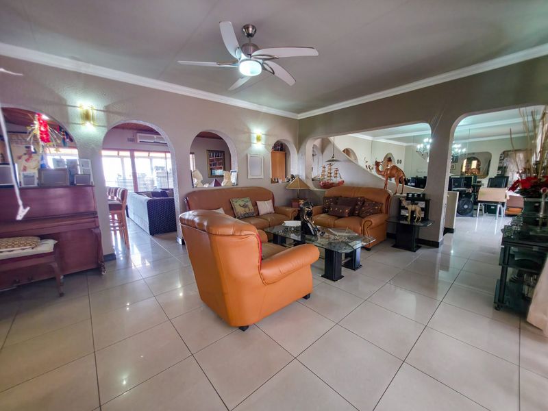 Spacious open-plan living area featuring tiled flooring, coved ceilings, and distinctive architectural archways connecting to adjacent rooms.
