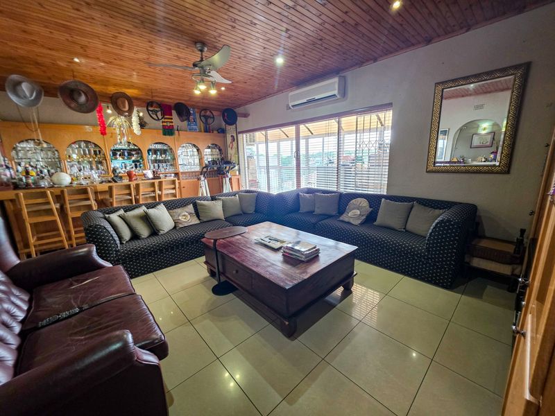 Spacious entertainment area featuring a built-in bar, timber-clad ceiling, tiled flooring, and split-system air conditioning, with direct access to the exterior via sliding doors.