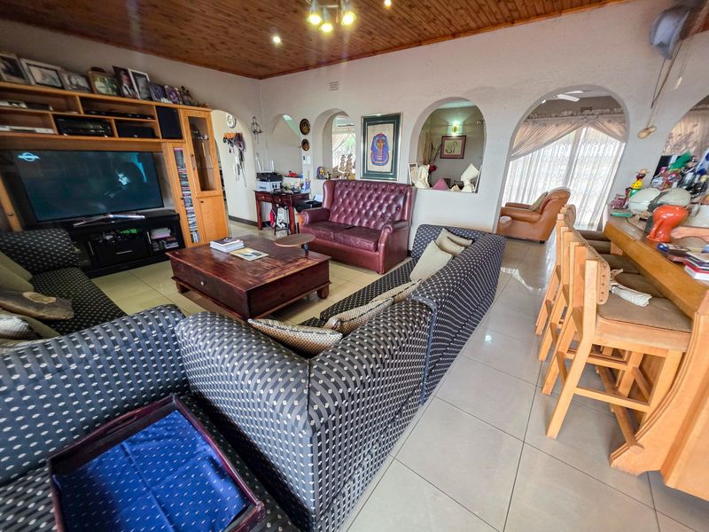 Spacious open-plan living area featuring tiled floors, a timber-clad ceiling, and distinctive arched wall openings connecting to adjacent spaces.