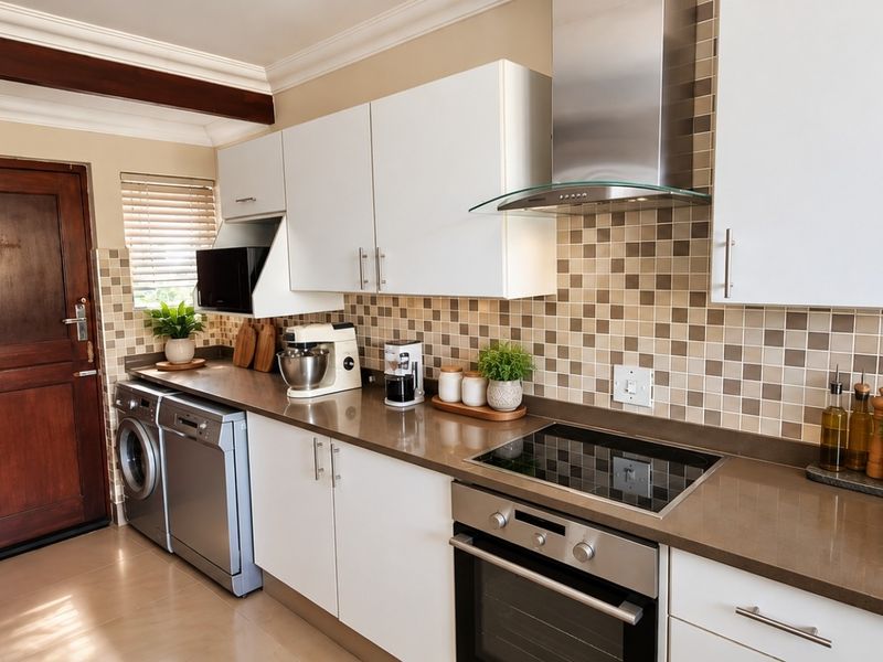 A well-maintained kitchen featuring modern white cabinetry, stone countertops, a mosaic tile backsplash, and integrated stainless steel appliances.