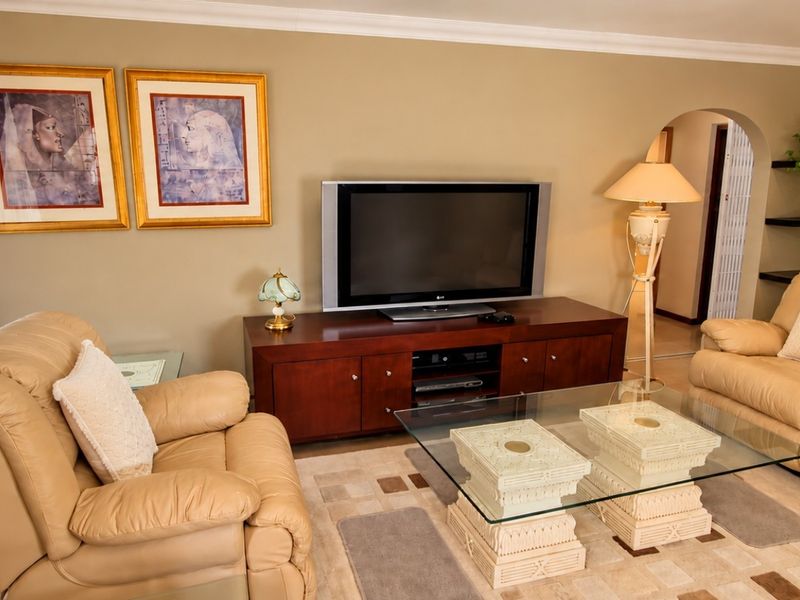 A comfortable living room featuring tiled flooring, an arched doorway, and built-in floating shelves, providing a functional and well-defined space.