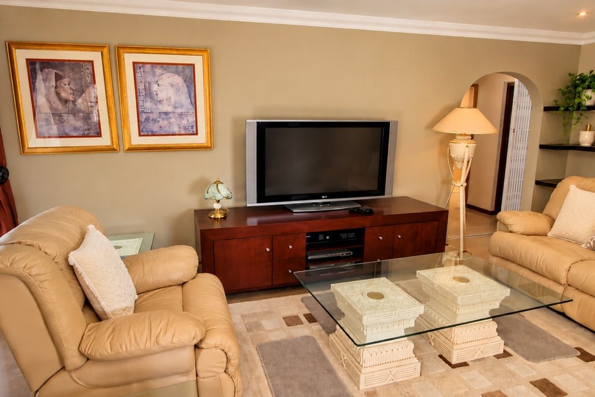 A comfortable living room featuring tiled flooring, an arched doorway, and built-in floating shelves, providing a functional and well-defined space.