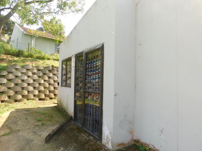 Rear exterior view of the townhouse showing a concrete retaining wall, security gate, and signs of exterior wall surface deterioration.