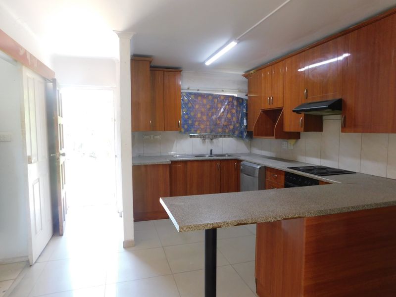 A functional kitchen featuring wooden cabinetry, granite countertops, a breakfast bar, and built-in cooking appliances, offering a practical layout for daily use.