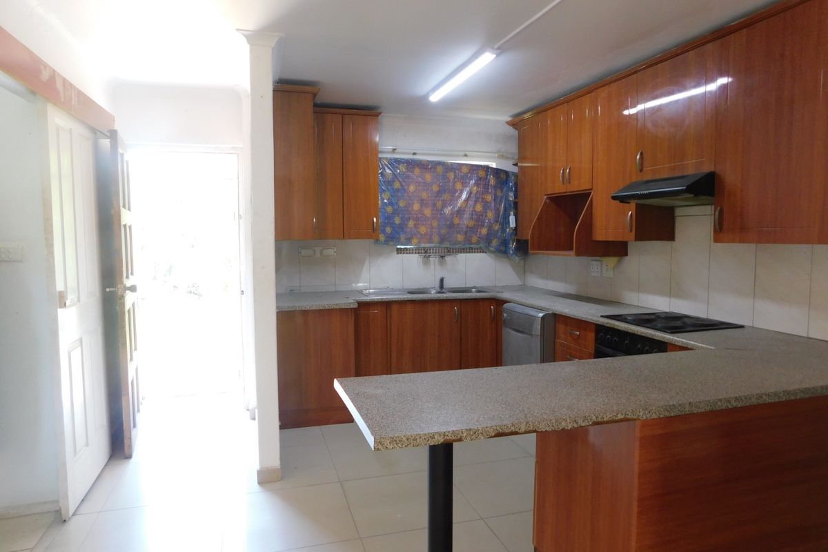 A functional kitchen featuring wooden cabinetry, granite countertops, a breakfast bar, and built-in cooking appliances, offering a practical layout for daily use.
