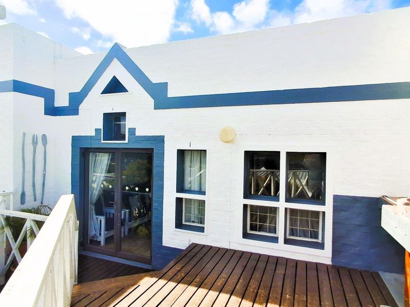 A private outdoor patio area featuring wooden decking, a built-in braai, and direct access to the interior through sliding glass doors.