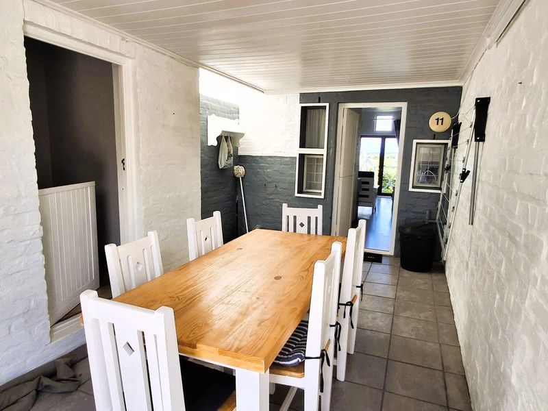 A covered outdoor patio area featuring tiled flooring, painted brick walls, and a practical wall-mounted drying rack.
