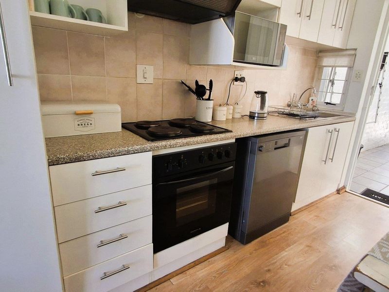 A functional kitchen featuring white cabinetry, laminate countertops, a built-in oven with electric hob, and a tiled backsplash.
