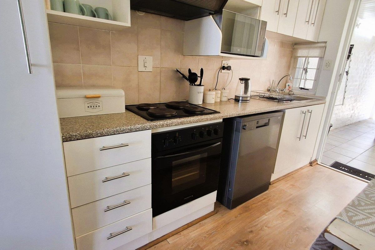 A functional kitchen featuring white cabinetry, laminate countertops, a built-in oven with electric hob, and a tiled backsplash.