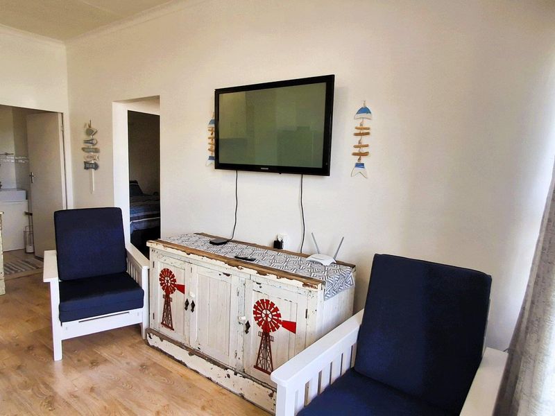 A living room area featuring light-toned laminate flooring and coved ceilings, providing a neutral base for interior design.