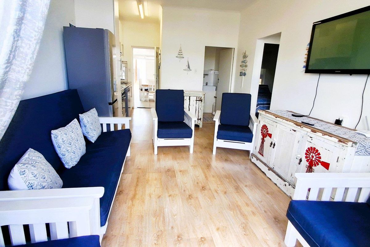 A bright living room area featuring light-toned laminate flooring, providing a functional space that connects to the kitchen and other rooms.