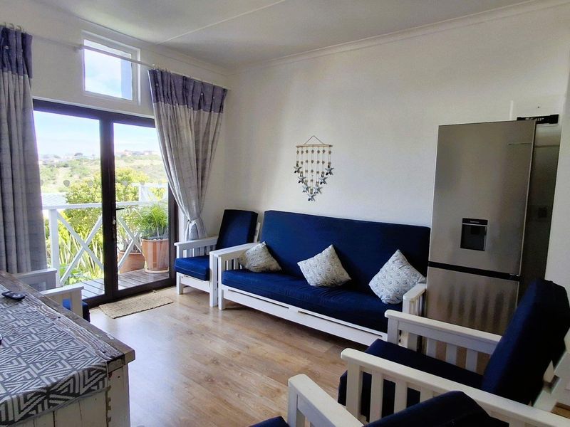 Open plan living area featuring laminate flooring and a sliding glass door providing direct access to a balcony with natural light.