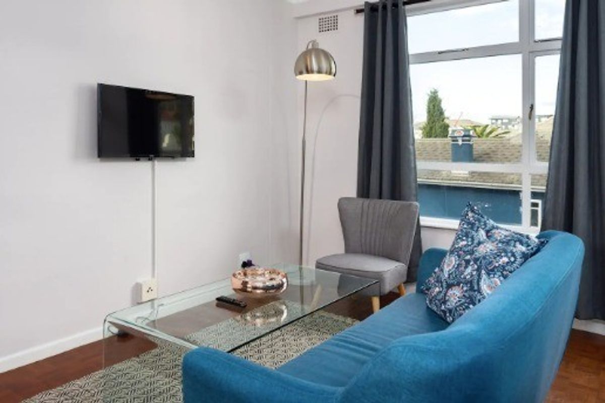 A bright living room featuring parquet flooring and a large window providing natural light and an exterior view.