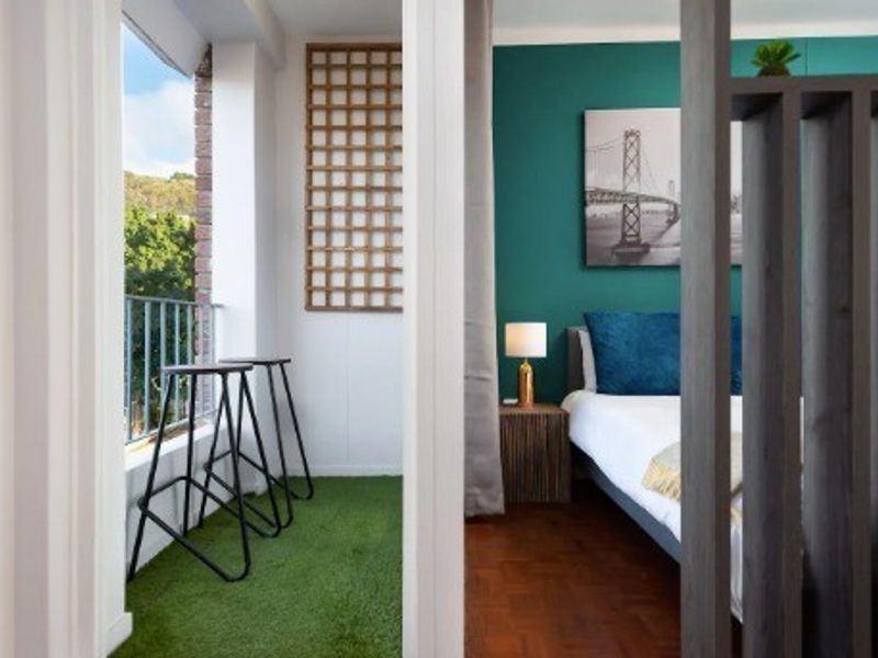 A bedroom featuring parquet flooring and a timber room divider, with direct access to a private balcony with metal railings.