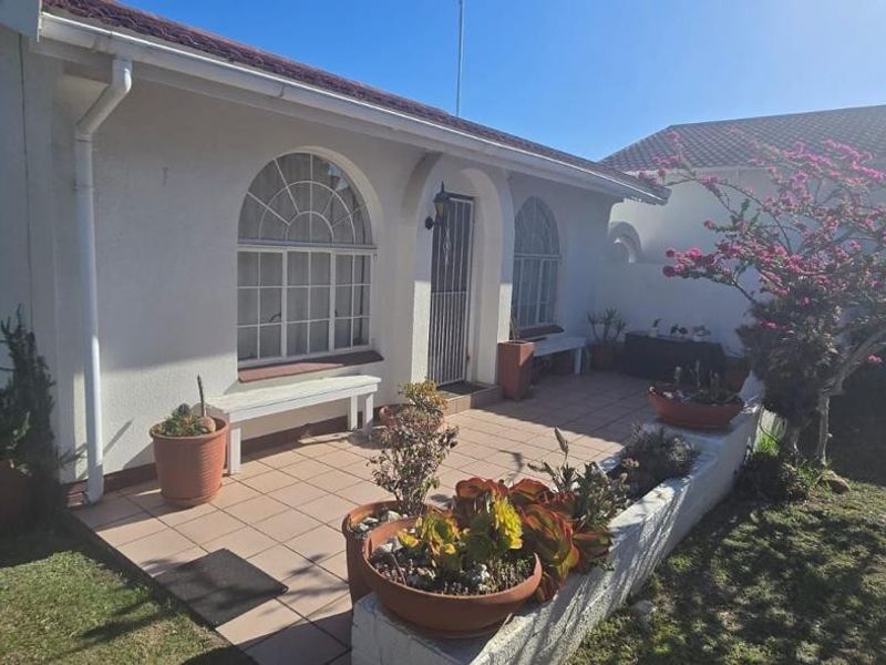 A well-maintained rear patio area featuring tiled flooring, arched windows, and a low masonry garden wall, providing a pleasant outdoor space.